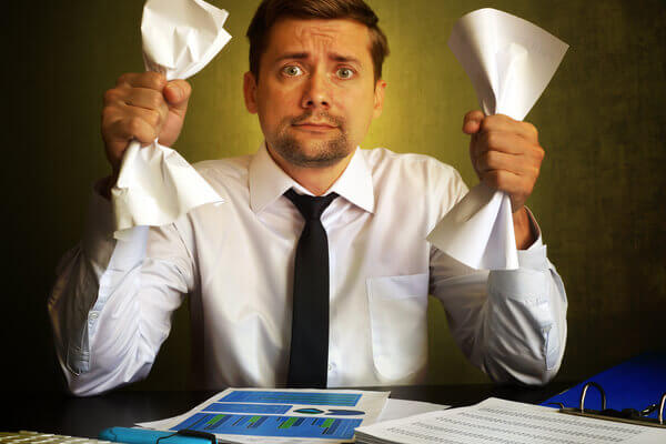 Man wearing white shirt and black tie holding paper in two hands thinking about how to stay erect when nervous